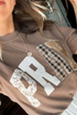 Tan t-shirt with 'PRAY' text in various patterns like patchwork.